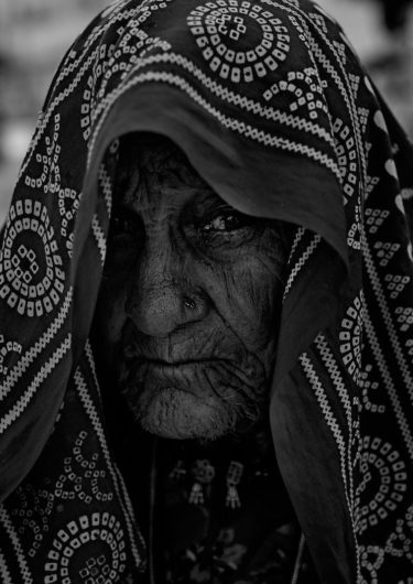 Black and White Photography with the title 'India 7'. Portrait of an Indian Woman with a scarf over her head.