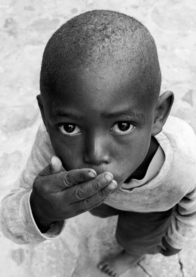 Black and white photogrpahy with the title 'Africa V'. A portrait of a little boy looking up to the camera. From the series 'Children of Tanzania'.